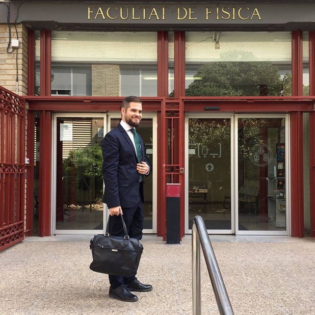 Vicent de traje frente a la puerta de la Facultat de Física antes de defender su tesis doctoral